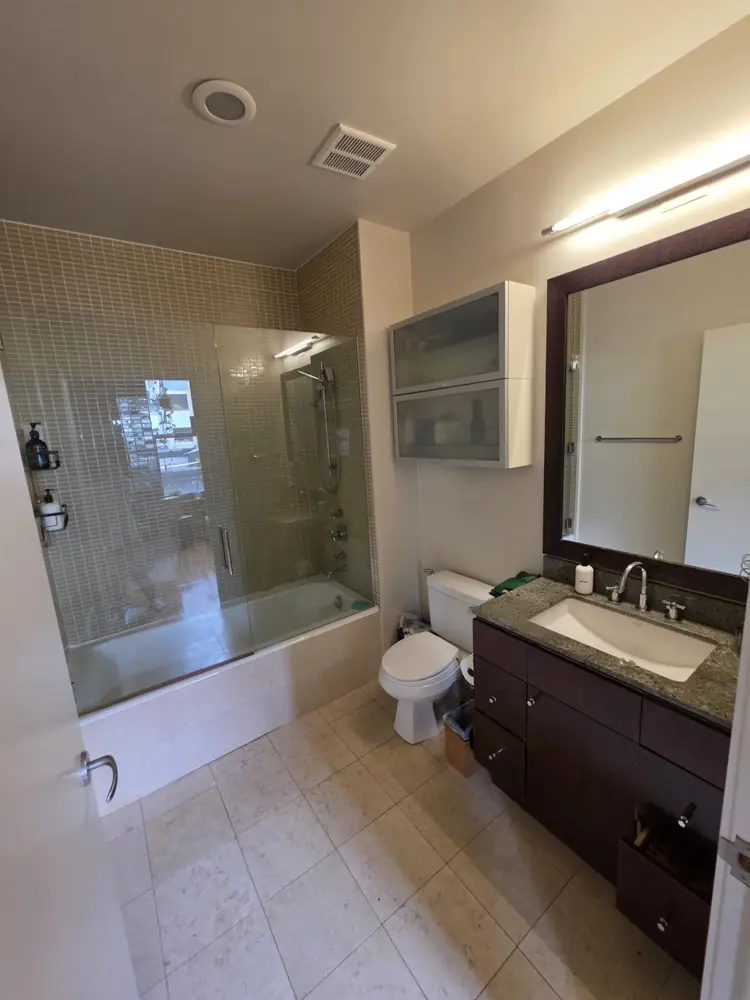 A freshly cleaned bathroom with a glass shower, tile floor and stone counter