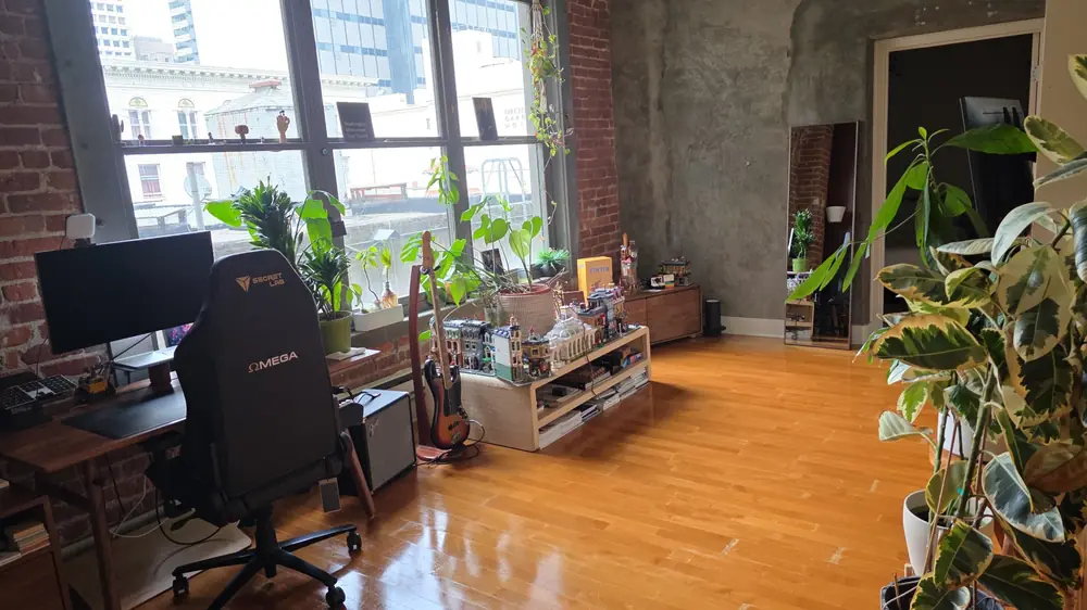 A clean loft with a desk, plants and gleaming wood floors